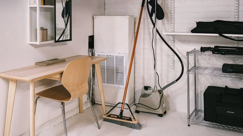 Close-up of people cleaning wooden floor with broom and dustpan indoors.